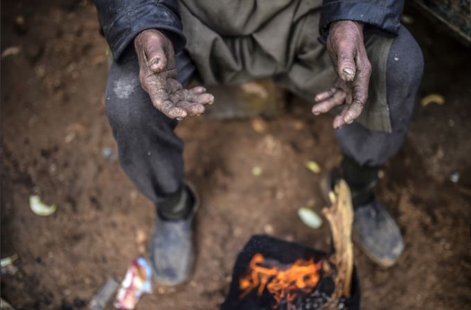 Un anciano busca calor en una improvisada fogata. Los refugiados se enfrentan al frío y el hambre tras huir de Aleppo, en Siria.