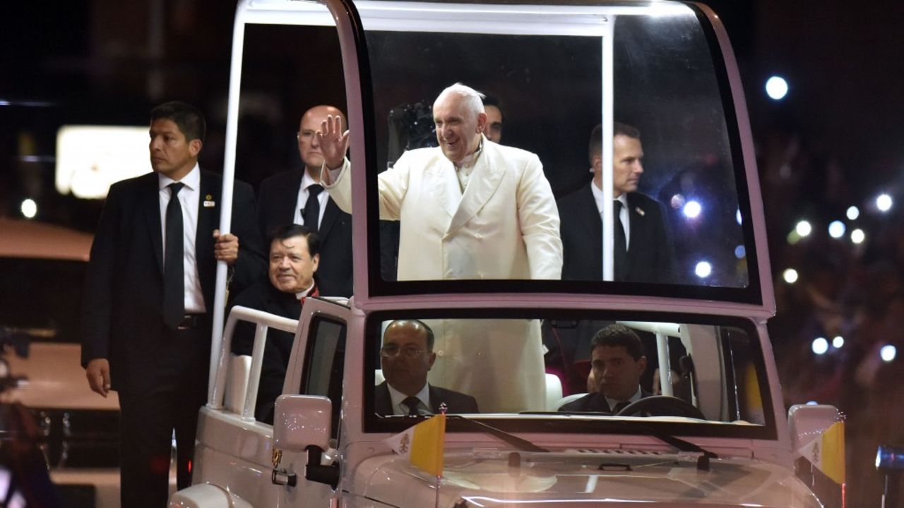 Pope Francis waves from the Popemobile upon his arrival in Mexico City on February 12, 2016. Catholic faithful flocked to the streets of Mexico City to greet Pope Francis on Friday after the pontiff held a historic meeting with the head of the Russian Orthodox Church in Cuba. AFP PHOTO/Yuri Cortez / AFP / YURI CORTEZ