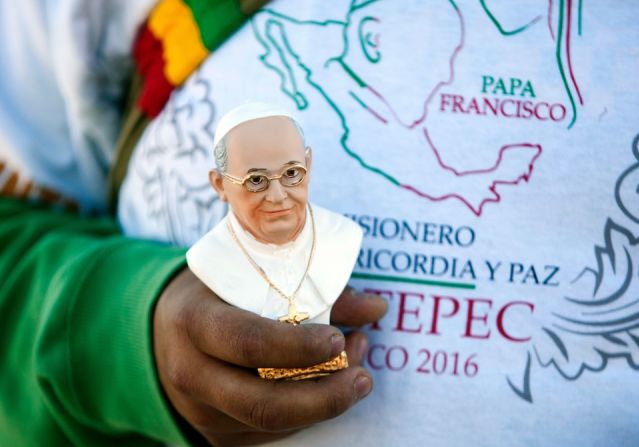 Un creyente católico espera la llegada del papa Francisco con un souvenir del pontífice en mano.