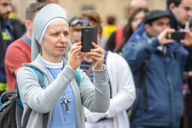 Una monja toma una fotografía en la plaza de San Pedro, el 26 de abril de 2014, antes de la canonización de los Papas Juan XXIII y Juan Pablo II.