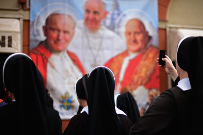 Los peregrinos se reúnen fuera de una tienda de recuerdos antes de la de la canonización de los Papas Juan XXIII y Juan Pablo II, el 26 de abril de 2014, en Ciudad del Vaticano.