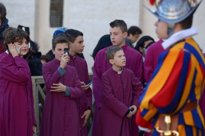 Los acólitos o monaguillos, quienes ayudan durante la celebración de las misas, toman fotos a la llegada del papa Francisco en la plaza de San Pedro en El Vaticano, el 25 de diciembre de 2015.