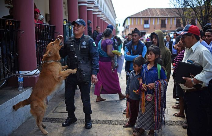 San Cristóbal de las Casas, Chiapas - Las personas rodean a un policía que vigila junto a su perro.