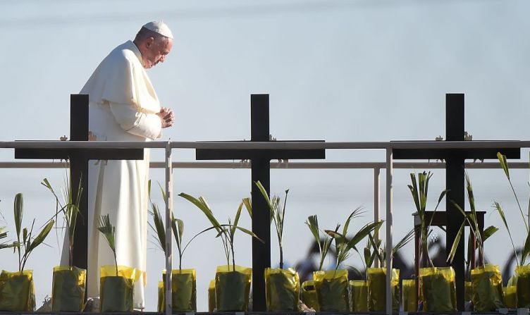 Francisco reza en una plataforma al lado de cruces en memoria de quienes murieron intentando cruzar la frontera en El Paso, Texas.