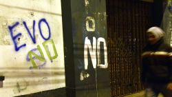 A man is seen walking next to a graffiti that reads "Evo no" after the referendum rejection in El Alto, Bolivia, on February 21. Bolivians on Sunday rejected leftist President Evo Morales' bid to seek a fourth term and potentially extend his presidency until 2025, local media reported. AFP/PHOTO/Aizar Raldes / AFP / AIZAR RALDES