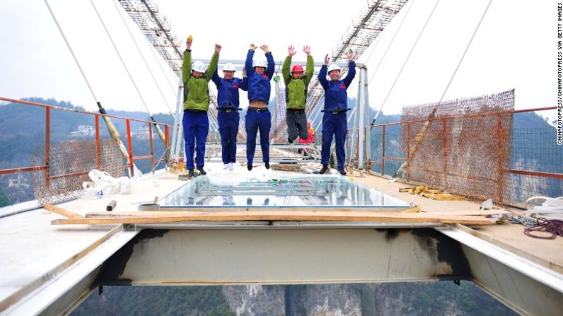 Un grupo de trabajadores posa para una foto mientras instalan un panel de vidrio en el puente de cristal de Zhangjiajie en China.