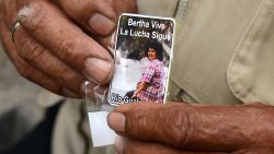 A man holds a card bearing a picture of murdered indigenous activist Berta Caceres reading "Bertha lives. The fight continues" during her funeral in La Esperanza, 200 km northwest of Tegucigalpa, on March 5, 2016. Honduran indigenous activist Berta Caceres, a renowned environmentalist whose family has labeled her killing an assassination, was shot dead on March 3 at her home in La Esperanza. Caceres rose to prominence for leading the indigenous Lenca people in a struggle against a hydroelectric dam project that would have flooded large areas of native lands and cut off water supplies to hundreds.  AFP PHOTO / ORLANDO SIERRA / AFP / ORLANDO SIERRA