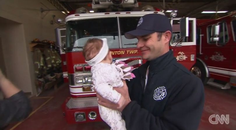 El bombero Ryan McCuen, del condado Clinton, Michigan, sostiene a su pequeña bebé, Camilla.