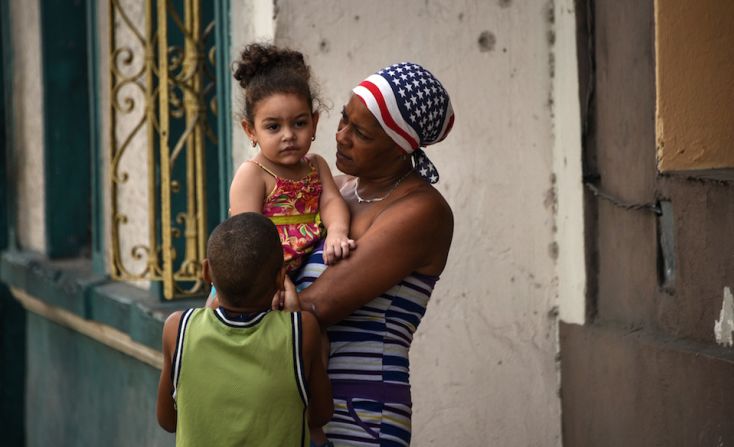 Una mujer con un pañuelo con los colores de la bandera de EE.UU. captada con sus hijos en una calle de La Habana, a unas horas de la llegada del presidente Barack Obama.