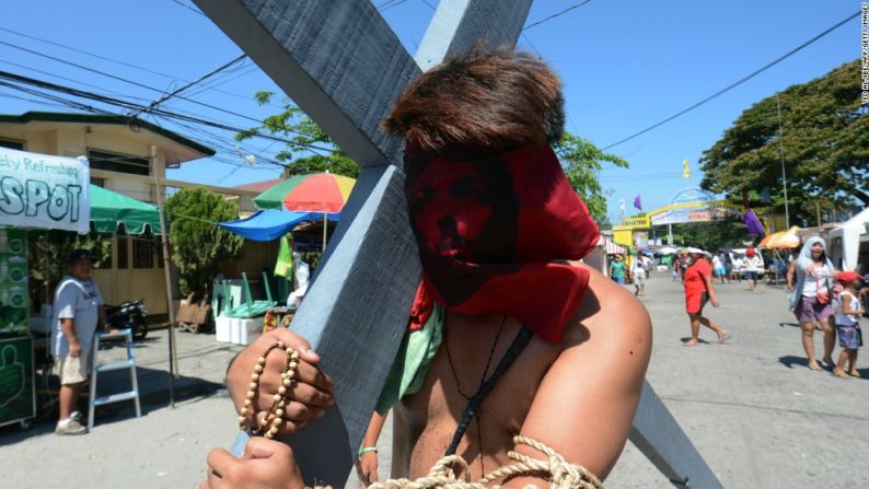 La imagen de Jesús cubre las caras de los penitentes mientras llevan la cruz durante la ceremonia de Semana Santa en la provincia de Pampanga.