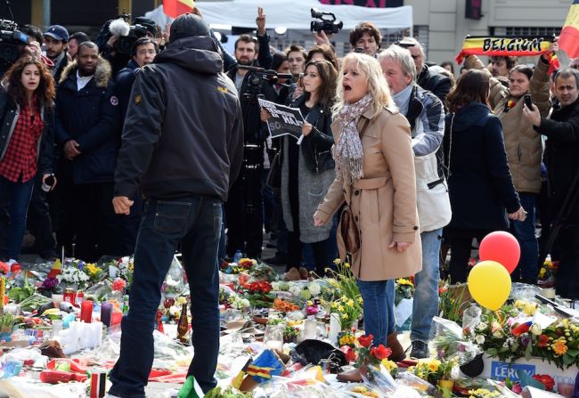 Una mujer encara a un manifestante de extrema derecha que camina sobre las flores depositadas en una plaza de Bruselas para recordar a las víctimas de los atentados.