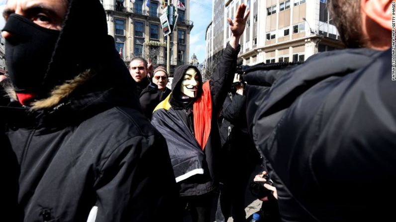 Un hombre enmascarado hace el saludo nazi al irrumpir en un acto de homenaje a víctimas de los ataques terroristas en Bruselas.