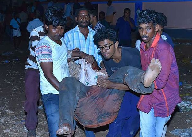 Varios voluntarios llevan en brazos a un herido grave por el incendio del templo de Puttigal, en la India.