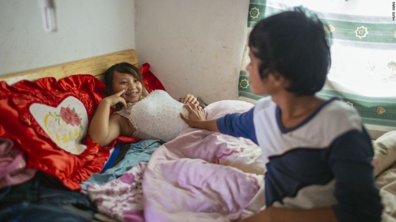 Wen, de 18 años, toca el vientre de su esposa embarazada Jie, de 13 años. Ellos viven juntos en el pueblo de Tangzibian del condado de Mengla en Yunnan.