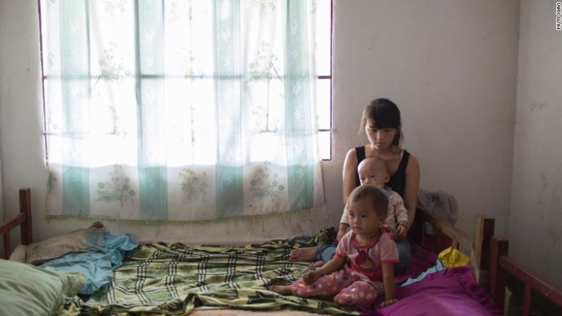 Mei, de 16 años, se sienta en la cama con su hija de 2 años y su hijo de 1 año en el pueblo de Wanhe del condado de Mengla en la provincia de Yunnan. Ella está casada desde hace 2 años. Ella y su esposo eran compañeros de clase en la escuela primaria y dejaron la escuela después de casarse.