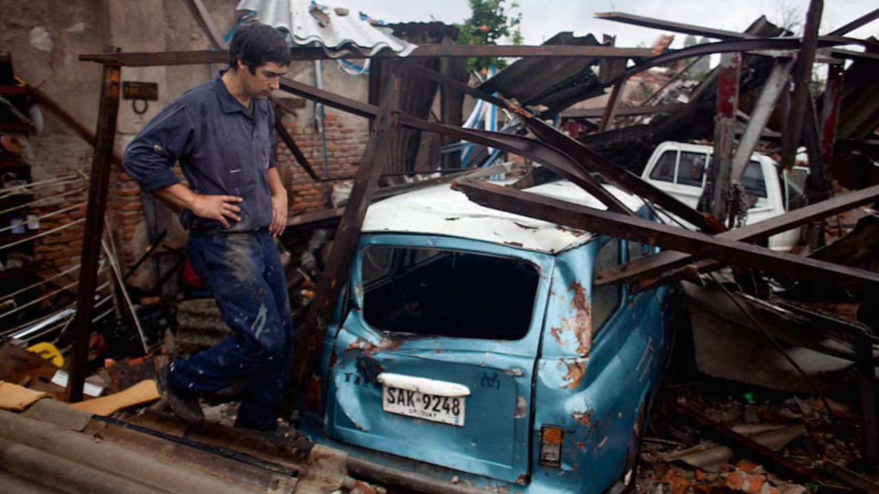 TOPSHOT - A man looks at a damaged car after a tornado in Dolores, Uruguay on April 16, 2016.
At least four people were killed and seven severely injured Friday by a tornado 265 km west of Montevideo, official sources reported. / AFP / Nicolas Garcia