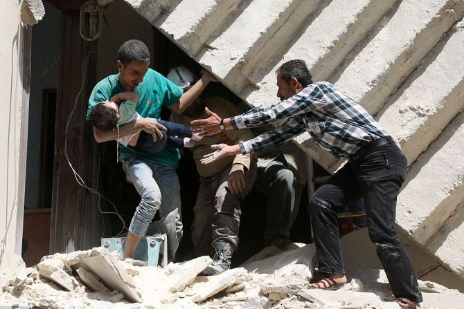 Dos hombres sirios evacúan a un niño pequeño que estaba en uno de los edificios destruidos por los bombardeos.