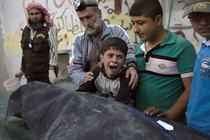 Un niño sirio llora al lado del cuerpo de un familiar que murió en el ataque a un hospital y edificios de un vecindario controlado por los rebeldes sirios.