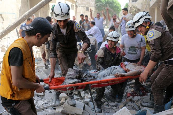 Voluntarios de la Defensa Civil de Siria retiran de un edificio el cuerpo sin vida de una víctima que dejaron los bombardeos en Alepo.