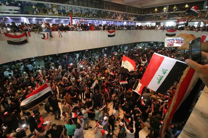 Manifestantes antigubernamentales ondean banderas de Iraq dentro de la llamada Zona Verde de Bagdad.