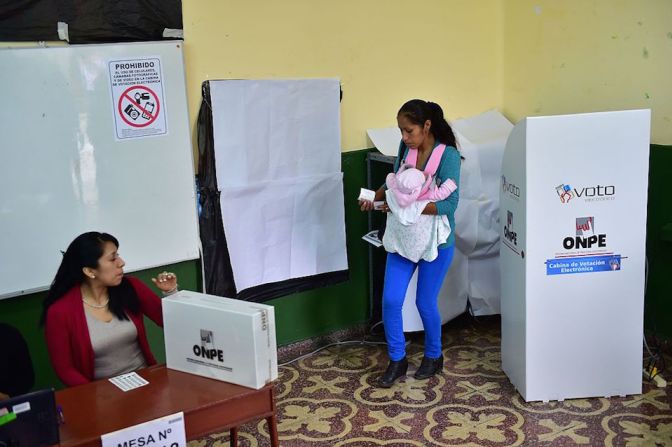 Con un bebé en brazos, una mujer acude a votar en el balotaje presidencial en Perú.