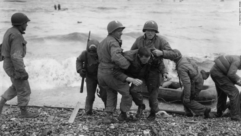 Tropas americanas ayudan a sus camaradas heridos luego de que le dispararan a sus lanchas de desembarco. Las fuerzas aliadas tuvieron cerca de 10.000 bajas asegurando las playas.