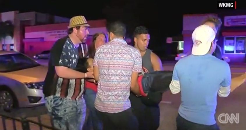 Una mujer es asistida por varios jóvenes tras el tiroteo en la discoteca Pulse de Orlando.