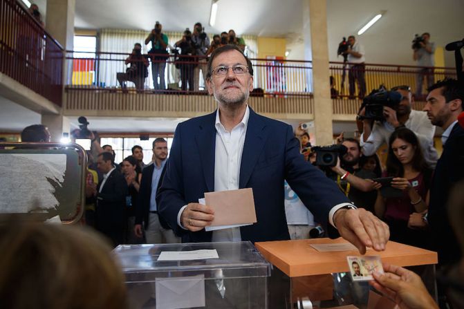 El presidente en funciones del gobierno español y líder del Partido Popular, Mariano Rajoy, entrega su documento nacional de identidad en un centro de votación en Madrid.