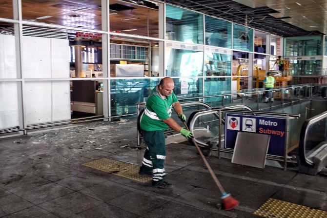 Un trabajador limpia los escombros un día después de las explosiones que perpetraron tres sujetos. Dos de ellos estaban en la terminal internacional y el tercero en el aparcamiento cercano.