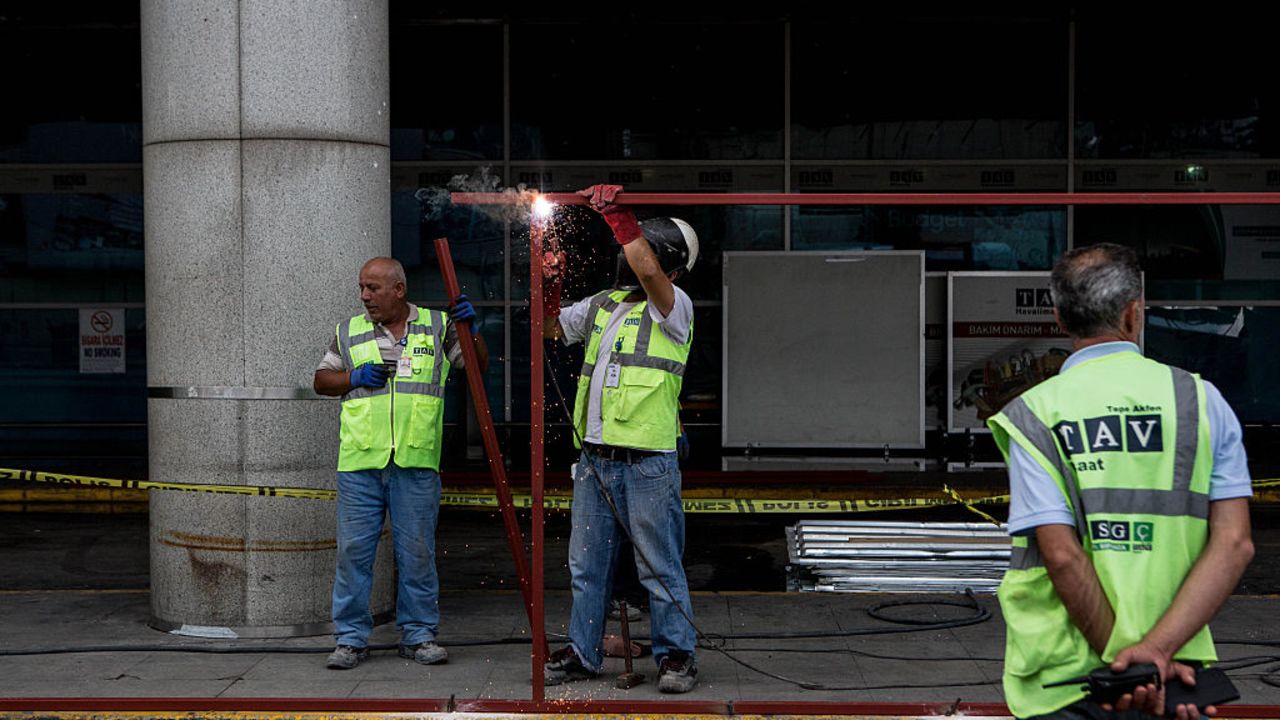 Un grupo de trabajadores reparan las áreas dañadas en el edificio de la terminal aérea. Los testigos describieron la carnicería y las escenas de pánico cuando los atacantes golpearon uno de los aeropuertos más activos del mundo.