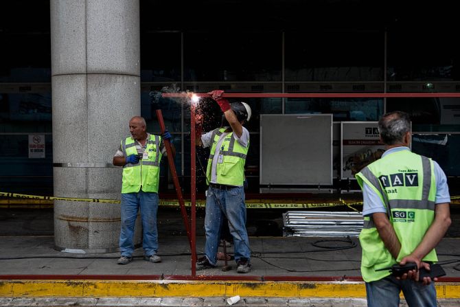 Un grupo de trabajadores reparan las áreas dañadas en el edificio de la terminal aérea. Los testigos describieron la carnicería y las escenas de pánico cuando los atacantes golpearon uno de los aeropuertos más activos del mundo.