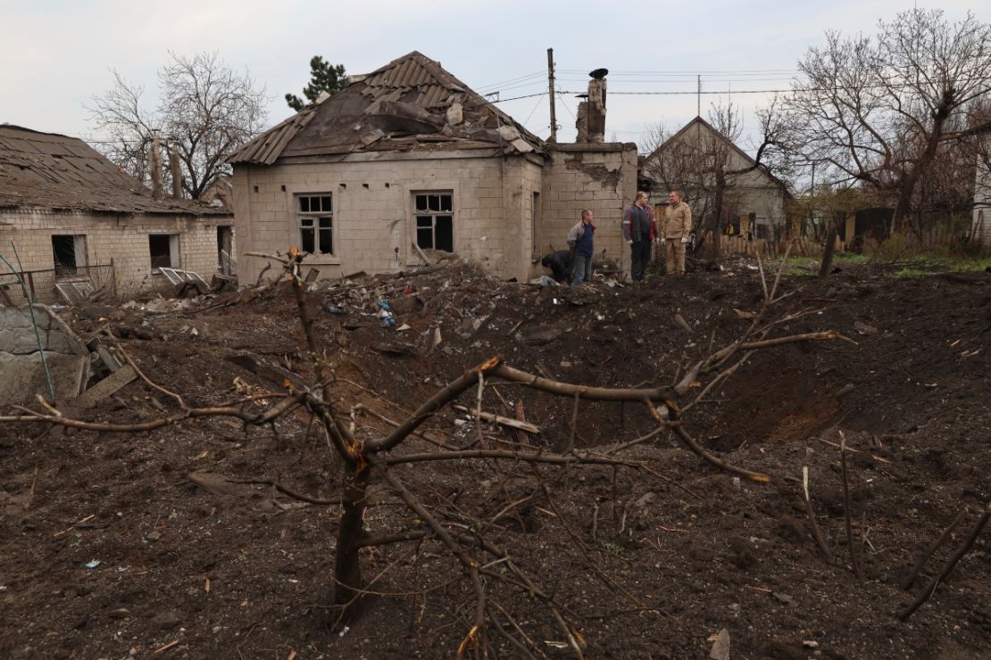 Residentes locales se paran cerca de un cráter que dejó un misil ruso en Zaporiyia, el domingo. Una niña de 11 años y su padre murieron en el ataque con misiles.