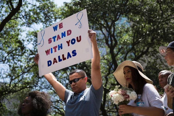 Un hombre sostiene un cartel que dice “Estamos con contigo, Dallas”, durante una vigilia en la Plaza de Acción de Gracias en Dallas, Texas, este viernes 8 de julio, luego de la muerte de cinco policías.