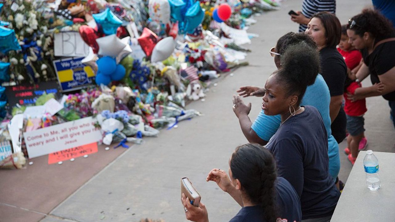 Mourners sing and clap their hands at the Police Headquarters memorial for officers killed in the recent sniper attack in Dallas, Texas on July 10, 2016.
The gunman who opened fire on Dallas officers during a protest against US police brutality, leaving five dead and seven others wounded, told negotiators he wanted to kill white cops, the city's police chief said July 8. / AFP / Laura Buckman