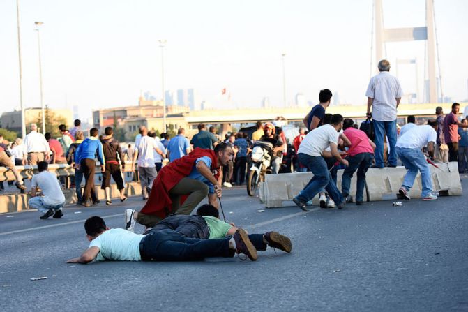 Varias personas se cubren cuando soldados y policías se enfrentan a tiros en el puente Bosphorus de Estambul, durante el intento de golpe de Estado en Turquía.