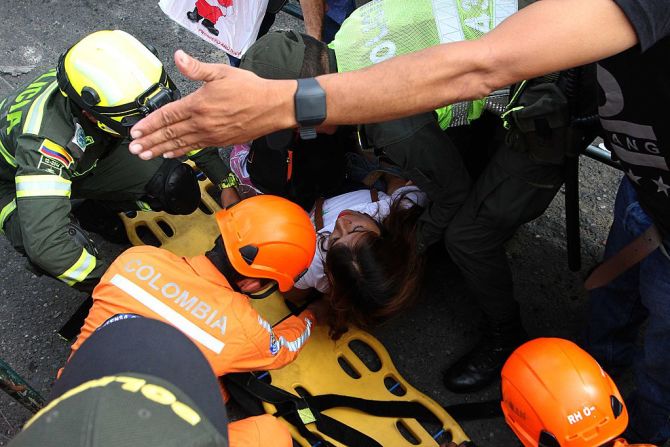 Miembros de la Defensa Civil de Colombia ayudan a una mujer que cayó mientras cruzaba el puente desde Táchira hacia Cúcuta.