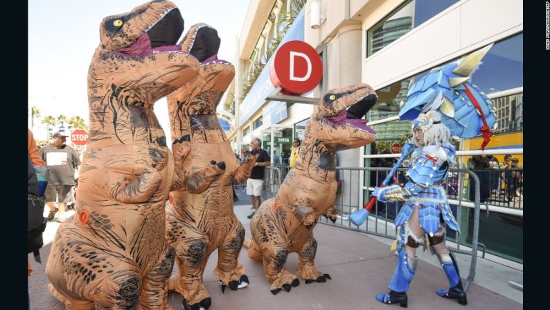 Katherine Masiewicz vestida como una cazadora de monstruos se enfrenta a un grupo de dinosaurios mientras posan para los fotógrafos a las afueras del centro de convenciones.