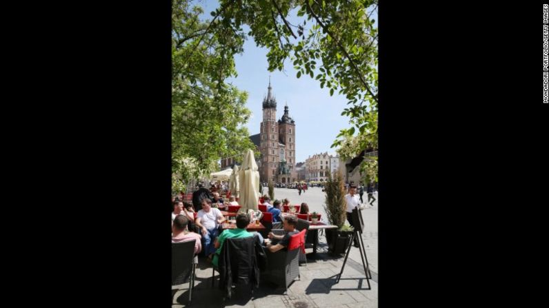 8. Cracovia, Polonia — Los turistas se sientan en la Rynek Glowny, la principal plaza de mercado de Cracovia. Esta es una de las ciudades más antiguas de Polonia y es hogar de una magnífica arquitectura medieval.