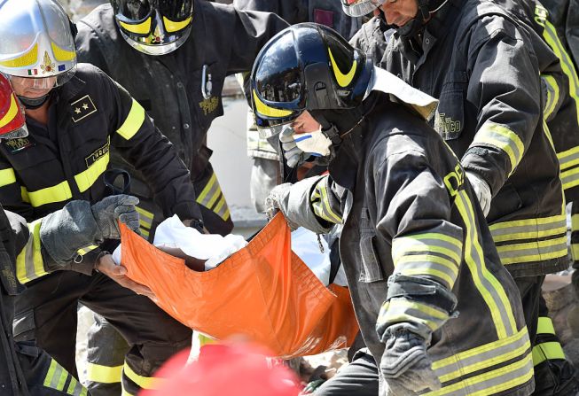 Rescatistas trabajan recuperando un cuerpo de un edificio dañado en Accumoli, Italia.