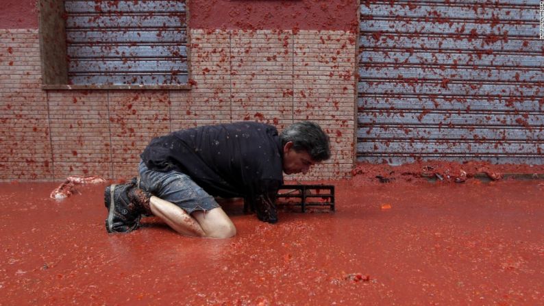 Tomatina en España — En esta imagen aparece un hombre desbloqueando un drenaje en medio de una inundación de tomates en las calles de Buñol, en Valencia, España, durante el tradicional evento de “guerra de tomates” conocido como la Tomatina, el 31 de agosto.