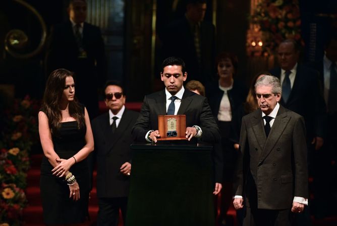 Gabriel Aguilera, hijo de Juan Gabriel, sostiene la urna con las cenizas de su padre, junto con el ministro de Cultura, Rafael Tovar, en el Palacio de Bellas Artes.