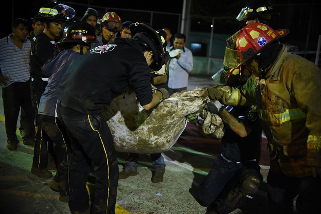 Los bomberos cargan un cuerpo recuperado de los escombros en Villa Nueva, Guatemala.