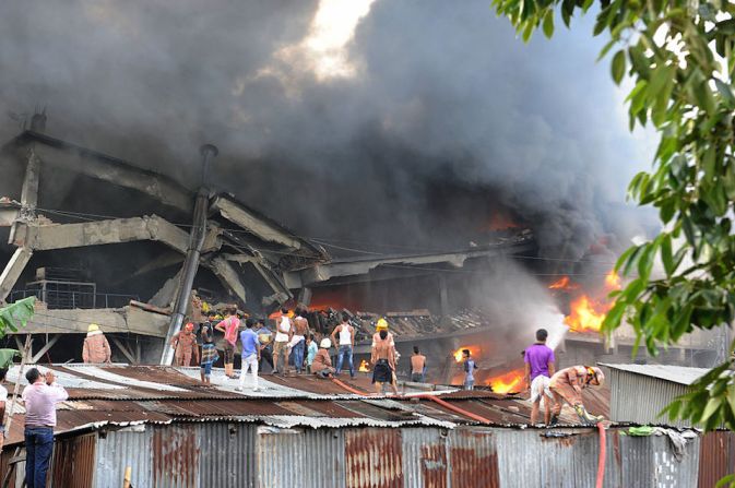 Vecinos de la fábrica siniestrada observan las enormes columnas de humo por el incendio en el inmueble, cerca de Dhaka, la capital de Bangladesh.