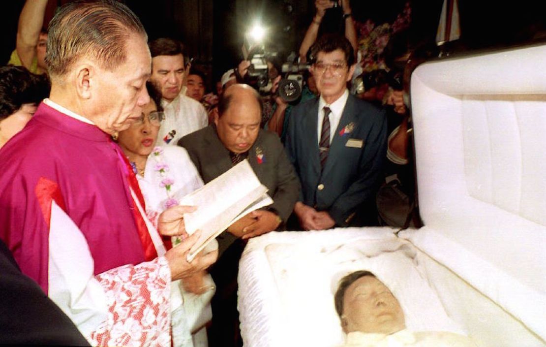 4 de septiembre de 1993. Monseñor Domingo Nebres, un sacerdote filipino y amigo de Ferdinand Marcos, hace una oración ante el cadáver del exdicator, horas antes del traslado del cuerpo de Honolulu a Filipinas. La mujer que aparece junto al sacerdote era la hermana de Marcos, Fortuna Barba.