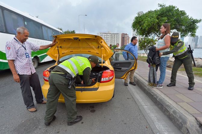 La policía revisa un automóvil y a sus ocupantes en un puesto de seguridad desplegado en Cartagena como medida de precaución, un día antes de la firma de la paz definitiva en Colombia.