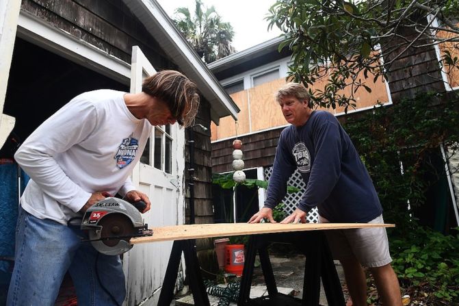 Dos hombres cortan tablas para colocar en sus ventanas en Atlantic Beach, Florida.