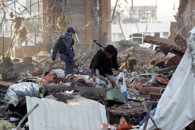 Dos hombres recolectan restos humanos de entre los escombros que dejaron los bombardeos en Sana, Yemen.