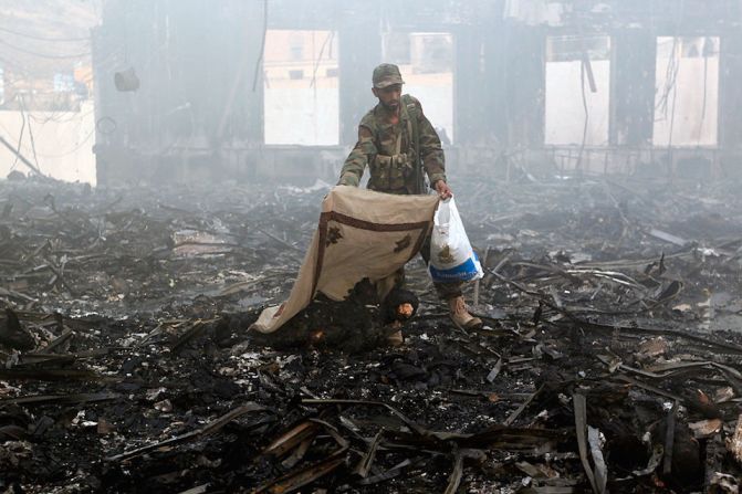 Un paramilitar cubre un cadáver en un edificio destruido por bombardeos de aviones de Arabia Saudita en la capital de Yemen.