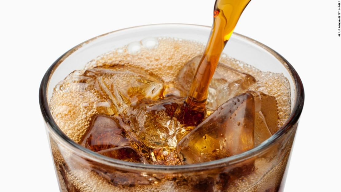 Soda being poured into glass with ice