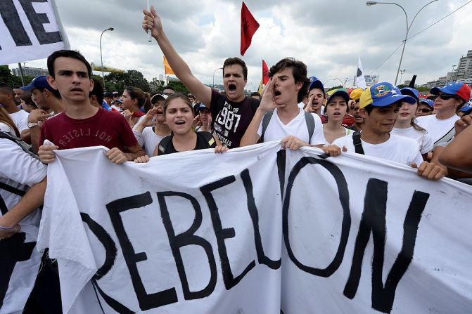 Un grupo de jóvenes sostiene una pancarta con la palabra “Rebelión”, mientras marchan contra el gobierno de Maduro, en una movilización masiva que se ha tomado varias ciudades del país desde tempranas horas del día.